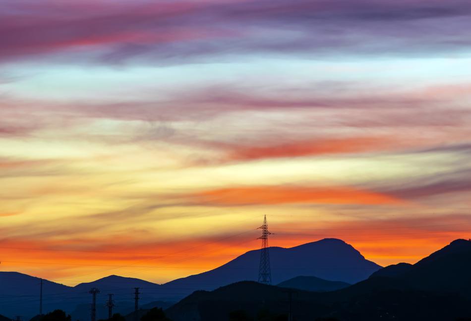 electric towers in the mountains against the backdrop of a colorful sunset