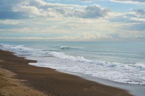 white clouds above the waves at the seaside