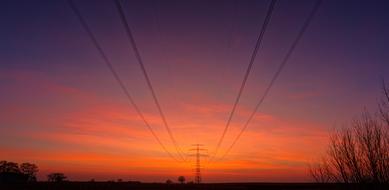 reinforced power lines against a background of orange-blue evening sky