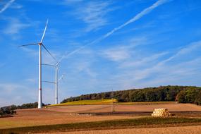 wind turbines stand along arable field