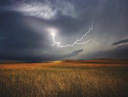 Stormy clouds with Lightning above field