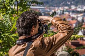 photographer in a leather jacket takes a picture of a city panorama