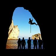 Silhouettes of the climbers, in the beautiful cave, near the water, with ripple