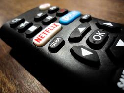 Black remote control with colorful buttons and red and white "Netflix" button