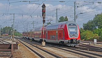 Red and grey double-deck electric multiple unit, among the green tree, under the cloudy sky in Treuchtlingen, Germany