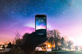 smartphone in hand against the background of the northern lights