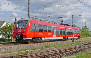 Red and grey regional train, on the Moselle Valley Railway, under the cloudy sky