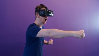 man punching while wearing virtual reality glasses at colorful background
