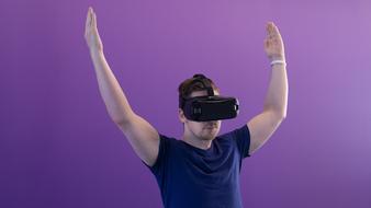 man with raised hands in virtual reality glasses