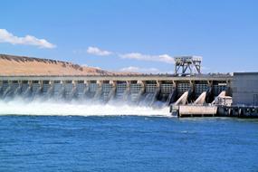 Beautiful dam with blue water, among the mountains, at blue sky with white clouds