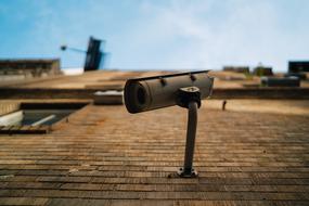 Close-up of a camera on the stone building, at blurred background, at blue sky with white clouds