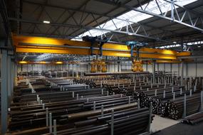 Yellow crane with gripping system, above the metal
