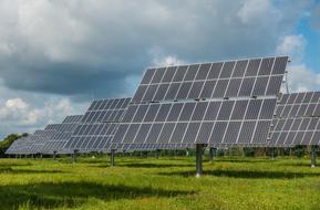 mounted solar panels on a green lawn under blue sky with white clouds