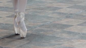 Beautiful, white feet of the ballerina, on the colorful pavement