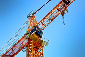 Close-up of the orange and red crane, at blue sky on background