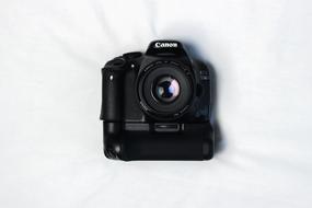 Beautiful, black Canon camera with colorful lens lying on the white surface