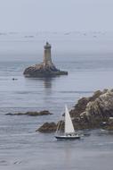 sailboat and lighthouse on the Atlantic coast in Brittany, France