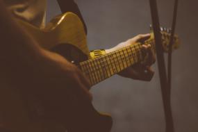 photo of an electric guitar in the hands of a musician