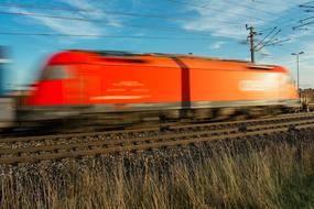 photo of a red locomotive moving at high speed in Austria