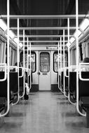 Black and white photo from the inside the train carriage, in the underground, with the seats