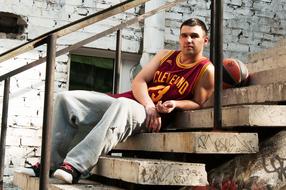 Basketball player, sitting on the stairs, with the ball, near the brick wall