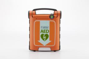 Orange, green and white Powerheart defibrillator, at white background