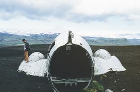 a man stands on the wing of a destroyed plane