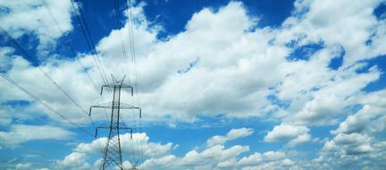 electrical supports with wires on a background of a blue sky with white clouds