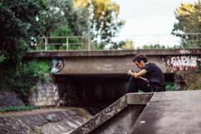 Photographer, Young boy Sitting with camera near bridge