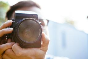 Close-up of the photographer, taking a photo, with the camera, in light