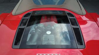 Engine of the red Ferrari car with view through the glass