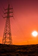electric tower against the orange sky at sunset