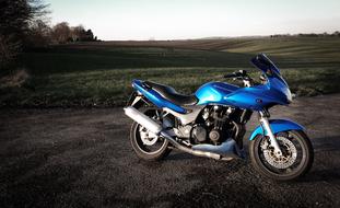 photo of a blue motorcycle in the countryside
