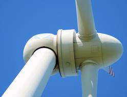 Close-up of the white windmill, in sunlight, at blue sky on background, in Poland