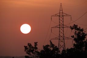 Silhouettes of the electric pylon, near the trees, in Shimoga, Karnataka, India, at colorful and beautiful sunset