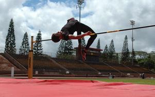 Athlete, doing high jump with the crossbar, on the colorful court