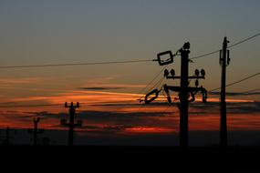 Power lines on the poles, on the beautiful landscape, at colorful sunset in the evening