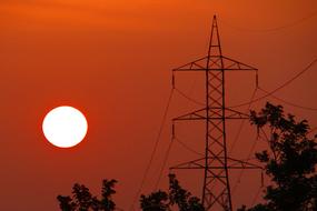 Silhouettes of the trees and electric pylon in Shimoga, Karnataka, India, at beautiful and colorful sunset