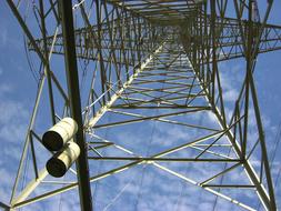 Low angle shot of the metal electric tower, under the blue sky with white clouds