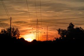 power lines over dark silhouettes of trees at sunset