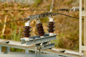 Brown insulators with cables, near the colorful field