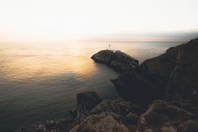 distant view of the lighthouse on the rocky coast at dusk