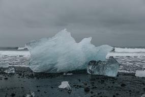 Beautiful, white and turquoise, gradient ice on the beach, under the cloudy sky