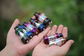 atomizers for electronic cigarettes in hands on a blurred background