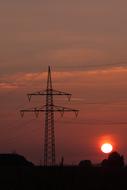 Silhouettes of the power lines, on the beautiful landscape, at colorful and beautiful sunset, with the clouds