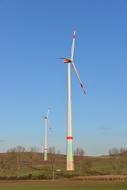Colorful wind turbines, on the beautiful and colorful field with plants, at blue sky on background