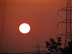 Electric pylons, among the trees, at beautiful and colorful sunset, in Shimoga, Karnataka, India