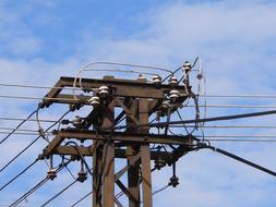 Close-up of an electricity transformer with electric cable, at beautiful blue sky with white clouds on background