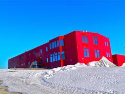 Red research station among the snow in Antarctica at blue sky background