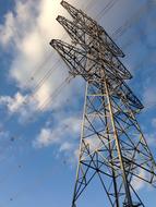 Power pole, with the cables, under the blue sky with clouds